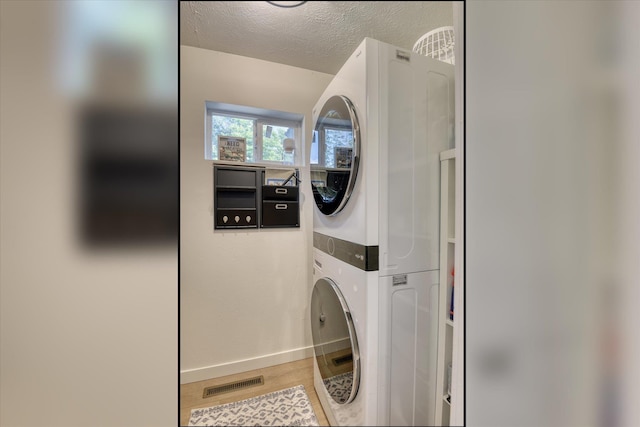 33348 Lakeview Ln, Valley, WA 99181 - washroom with stacked washer and clothes dryer, a textured ceiling, and wood finished floors