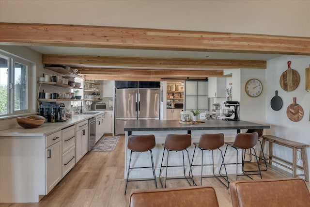 33348 Lakeview Ln, Valley, WA 99181 - kitchen featuring appliances with stainless steel finishes, beam ceiling, a breakfast bar, open shelves, and white cabinetry