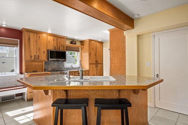 203 W 21st Ave, Spokane, WA 99203 - kitchen with stainless steel microwave, range, light tile patterned floors, tile countertops, and a breakfast bar
