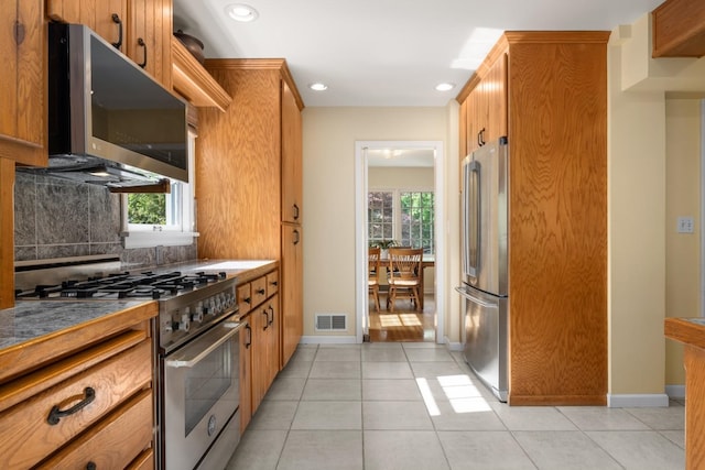 203 W 21st Ave, Spokane, WA 99203 - kitchen with stainless steel appliances, light tile patterned floors, brown cabinetry, recessed lighting, and backsplash