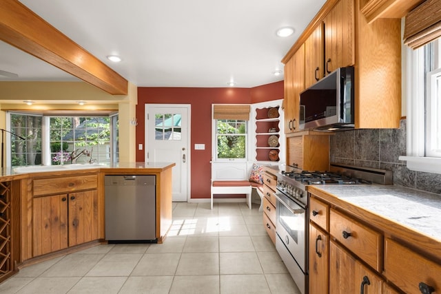 203 W 21st Ave, Spokane, WA 99203 - kitchen with stainless steel appliances, decorative backsplash, light tile patterned floors, brown cabinetry, and tile countertops