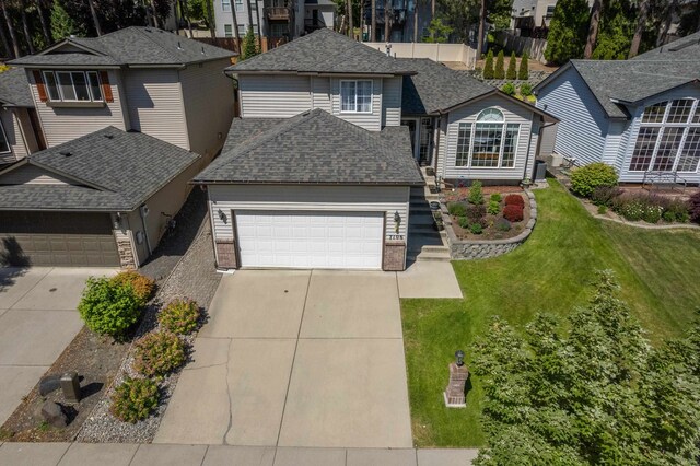 7106 S Moran View St, Spokane, WA 99224 - view of front of home with a garage, concrete driveway, a front yard, roof with shingles, and a residential view
