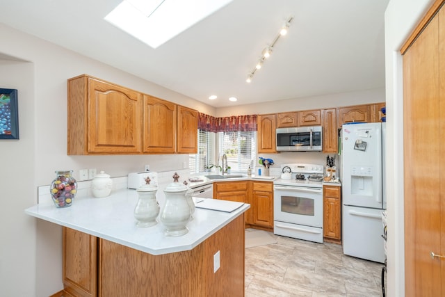 7106 S Moran View St, Spokane, WA 99224 - kitchen featuring white appliances, a peninsula, light countertops, a skylight, and brown cabinets