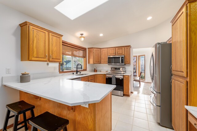 5622 E Sheffield, Colbert, WA 99005 - kitchen featuring stainless steel appliances, a peninsula, lofted ceiling, a kitchen bar, and brown cabinets