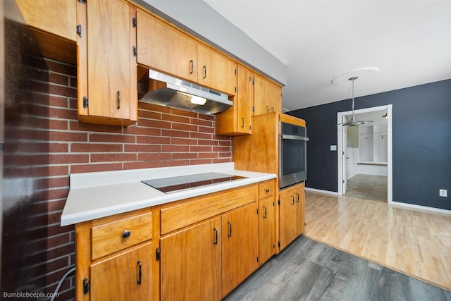 11918 E Grace Ave, Spokane Valley, WA 99206 - kitchen with under cabinet range hood, black electric cooktop, oven, wood finished floors, and light countertops