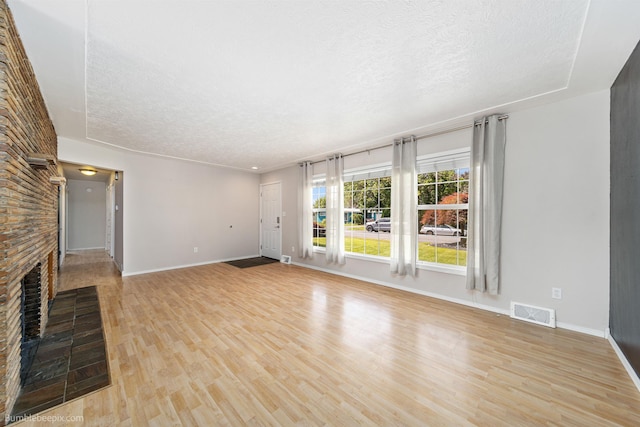 11918 E Grace Ave, Spokane Valley, WA 99206 - unfurnished living room featuring a textured ceiling, light wood-style flooring, and a fireplace