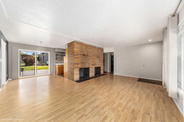 11918 E Grace Ave, Spokane Valley, WA 99206 - unfurnished living room featuring a fireplace, light wood-type flooring, a textured ceiling, and recessed lighting