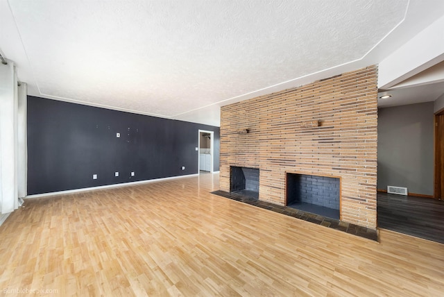 11918 E Grace Ave, Spokane Valley, WA 99206 - unfurnished living room with a fireplace, wood finished floors, and a textured ceiling