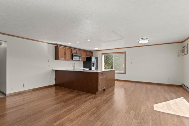 214 W 6th Ave Apt 201, Spokane, WA 99204 - kitchen featuring stainless steel appliances, crown molding, a peninsula, light wood finished floors, and brown cabinetry