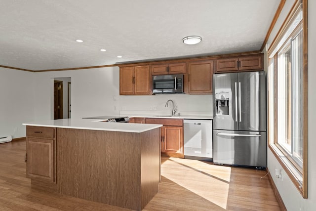 214 W 6th Ave Apt 201, Spokane, WA 99204 - kitchen featuring stainless steel appliances, light wood finished floors, crown molding, light countertops, and brown cabinets
