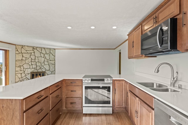 214 W 6th Ave Apt 201, Spokane, WA 99204 - kitchen featuring appliances with stainless steel finishes, a peninsula, light wood-style flooring, light countertops, and crown molding