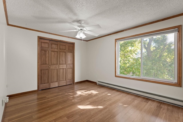 214 W 6th Ave Apt 201, Spokane, WA 99204 - unfurnished bedroom with a baseboard heating unit, wood finished floors, a closet, ornamental molding, and a textured ceiling