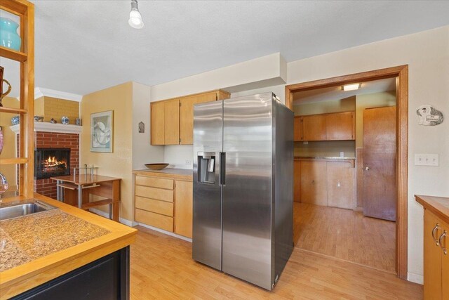3157 E 35th Ave, Spokane, WA 99223 - kitchen featuring stainless steel fridge with ice dispenser, light wood-type flooring, a fireplace, and light countertops