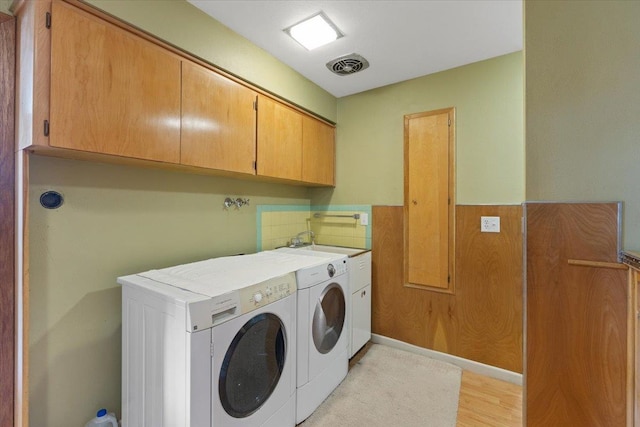3157 E 35th Ave, Spokane, WA 99223 - laundry area featuring cabinet space, washer and clothes dryer, wainscoting, and light wood-type flooring