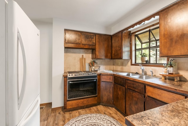 10818 N Humboldt Dr, Spokane, WA 99218 - kitchen with freestanding refrigerator, range, light wood-style flooring, and tasteful backsplash