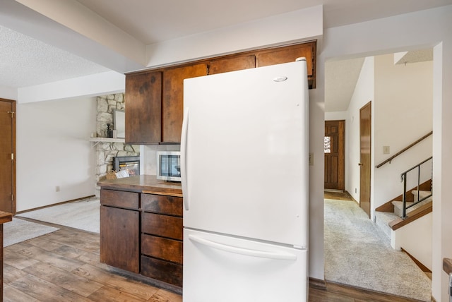 10818 N Humboldt Dr, Spokane, WA 99218 - kitchen with freestanding refrigerator, wood finished floors, stainless steel microwave, and a stone fireplace