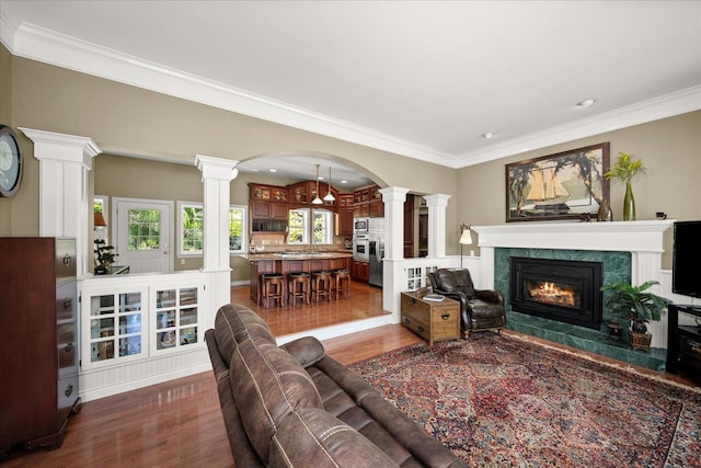 2008 S Zephyr Rd, Liberty Lake, WA 99019 - living room featuring decorative columns, dark wood finished floors, a tile fireplace, ornamental molding, and arched walkways