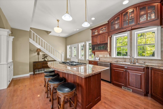 2008 S Zephyr Rd, Liberty Lake, WA 99019 - kitchen featuring stainless steel appliances, light wood-type flooring, light stone counters, a kitchen bar, and a kitchen island