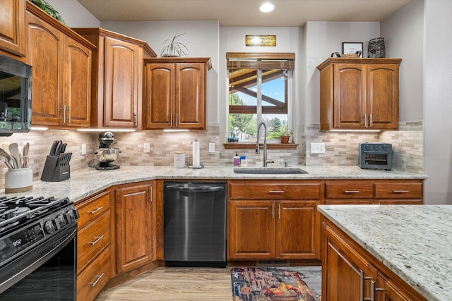 2813 S Steen Ln, Greenacres, WA 99016 - kitchen with dishwashing machine, black range with gas stovetop, light stone counters, light wood-type flooring, and brown cabinetry