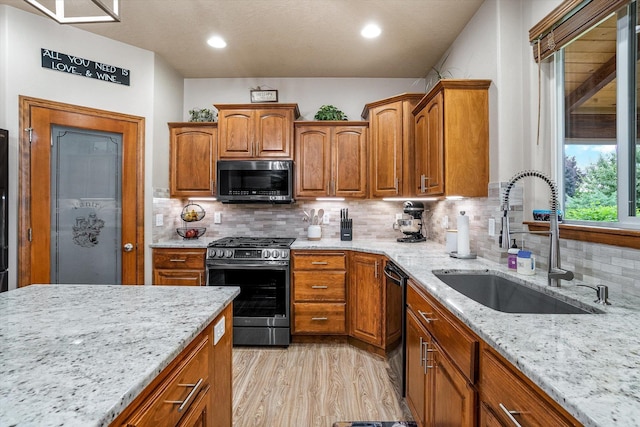 2813 S Steen Ln, Greenacres, WA 99016 - kitchen featuring stainless steel range with gas stovetop, black dishwasher, light stone counters, light wood-style floors, and brown cabinets