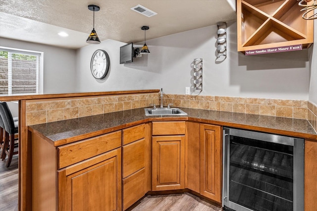 2813 S Steen Ln, Greenacres, WA 99016 - kitchen with wine cooler, light wood-style flooring, brown cabinets, dark countertops, and a peninsula