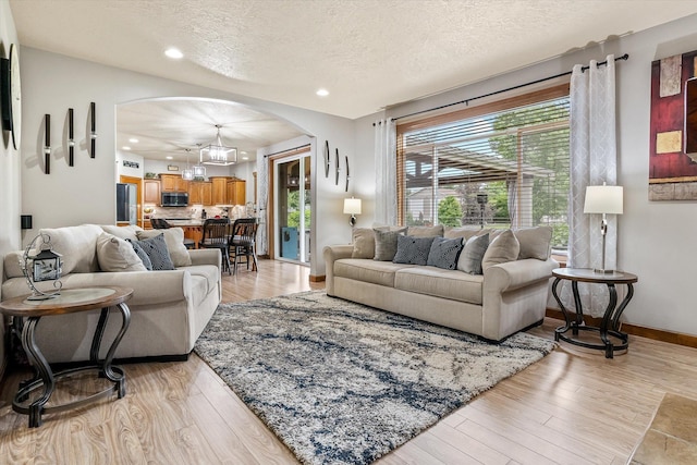2813 S Steen Ln, Greenacres, WA 99016 - living area featuring arched walkways, a textured ceiling, light wood-type flooring, and recessed lighting