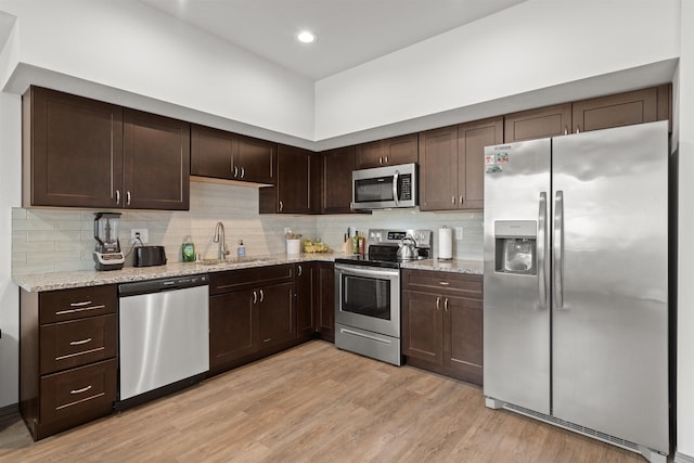 419 E E St, Deer Park, WA 99006 - kitchen featuring appliances with stainless steel finishes, dark brown cabinetry, light wood-style floors, tasteful backsplash, and light stone countertops