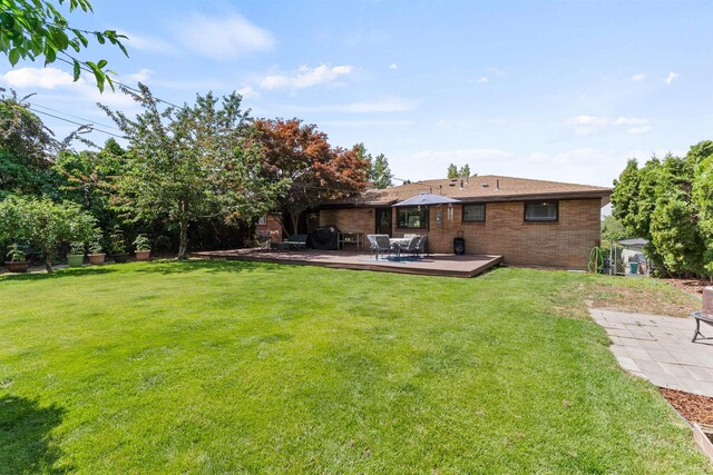 5704 N Sutherlin St, Spokane, WA 99205 - rear view of property with a wooden deck, a yard, and brick siding