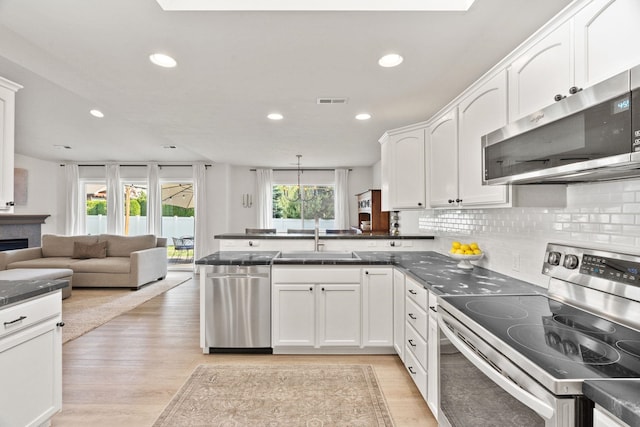 2808 E 62nd Ln, Spokane, WA 99223 - kitchen with appliances with stainless steel finishes, dark countertops, a peninsula, white cabinetry, and recessed lighting