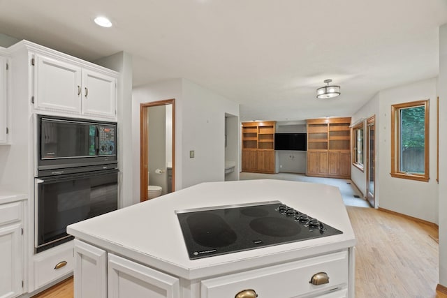 13419 N Whitehouse Ct, Spokane, WA 99208 - kitchen with black appliances, white cabinets, light countertops, light wood-style flooring, and a kitchen island