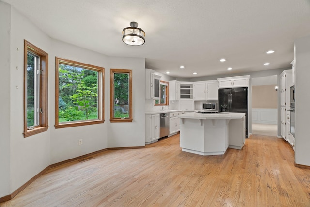 13419 N Whitehouse Ct, Spokane, WA 99208 - kitchen with appliances with stainless steel finishes, light countertops, a kitchen island, light wood-style floors, and white cabinetry