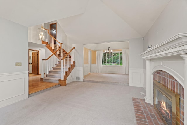 13419 N Whitehouse Ct, Spokane, WA 99208 - unfurnished living room featuring a chandelier, a fireplace, a decorative wall, stairs, and carpet flooring