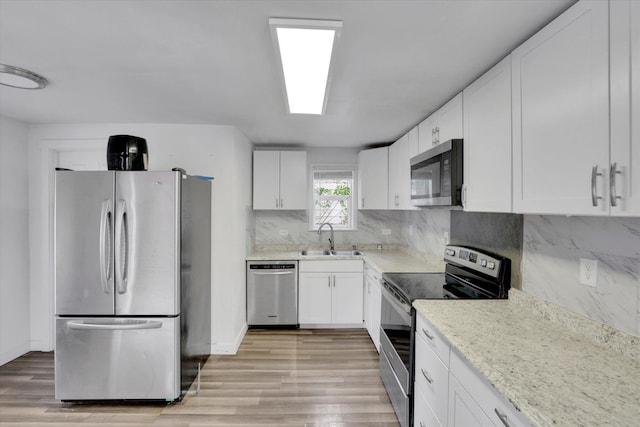 2403 W Mallon Ave, Spokane, WA 99201 - kitchen featuring appliances with stainless steel finishes, light wood-style floors, white cabinetry, and tasteful backsplash