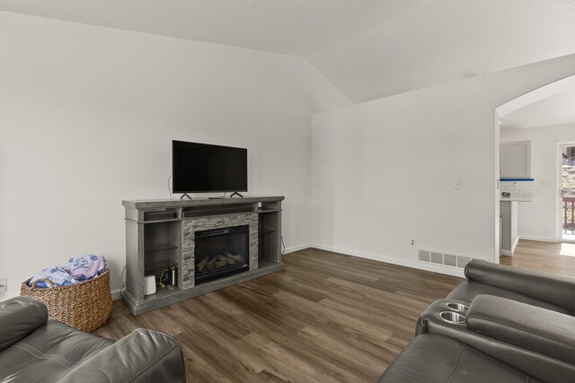18108 E Crescent Dr, Greenacres, WA 99016 - living area featuring arched walkways, vaulted ceiling, dark wood-type flooring, and a stone fireplace
