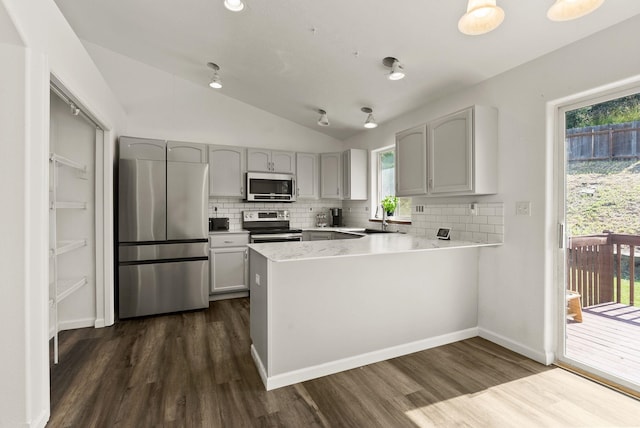 18108 E Crescent Dr, Greenacres, WA 99016 - kitchen featuring appliances with stainless steel finishes, lofted ceiling, backsplash, dark wood finished floors, and a peninsula