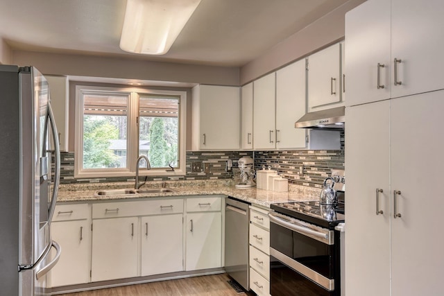 1026 W Bellwood Dr, Spokane, WA 99218 - kitchen featuring appliances with stainless steel finishes, exhaust hood, tasteful backsplash, and white cabinets