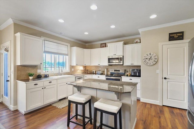 1716 W Country Hunt Ln, Spokane, WA 99224 - kitchen with stainless steel appliances, a kitchen breakfast bar, white cabinets, a center island, and crown molding