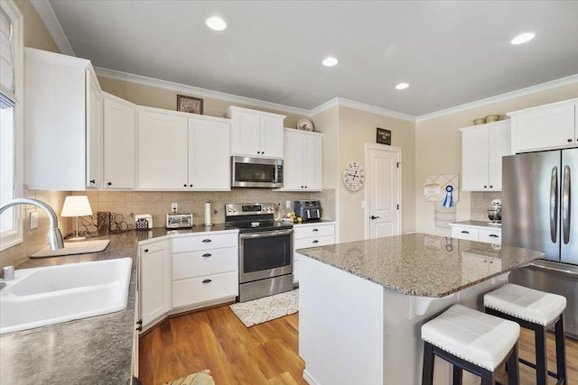 1716 W Country Hunt Ln, Spokane, WA 99224 - kitchen with appliances with stainless steel finishes, backsplash, a kitchen island, ornamental molding, and a kitchen breakfast bar