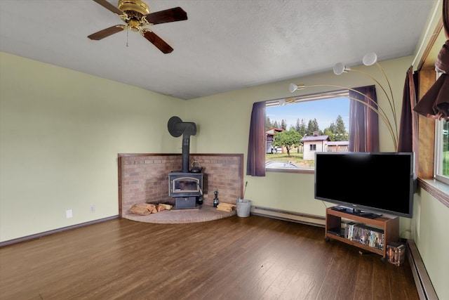 42503 N Regal Rd, Elk, WA 99009 - living area with a baseboard radiator, a wood stove, wood finished floors, a baseboard heating unit, and a ceiling fan