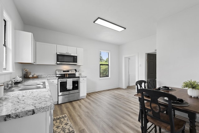 411 S Ferrall St, Spokane, WA 99202 - kitchen with stainless steel appliances, light countertops, white cabinetry, and light wood finished floors