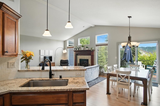 116 W Bristol Ave, Spokane, WA 99224 - kitchen featuring brown cabinetry, plenty of natural light, vaulted ceiling, a fireplace, and light wood-type flooring