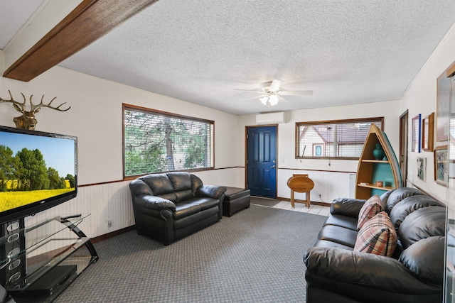 6519I Myrtle Dr, Nine Mile Falls, WA 99026 - carpeted living area with a wall unit AC, a wainscoted wall, a ceiling fan, and a textured ceiling