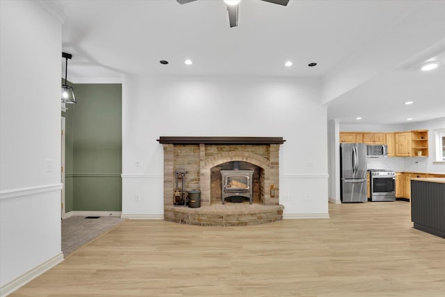13306 N Muzzy Rd, Newman Lake, WA 99025 - unfurnished living room with a wood stove, light wood-style floors, ceiling fan, recessed lighting, and crown molding