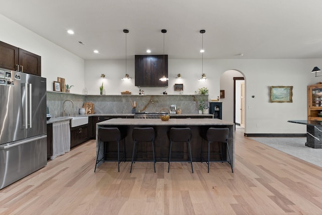 7617 S Cedar Rd, Spokane, WA 99224 - kitchen featuring high end refrigerator, light countertops, arched walkways, light wood-type flooring, and tasteful backsplash