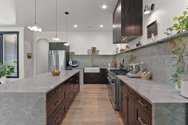 7617 S Cedar Rd, Spokane, WA 99224 - kitchen featuring stainless steel appliances, light wood-style flooring, tasteful backsplash, dark brown cabinetry, and light stone counters