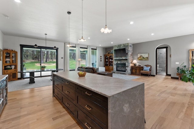 7617 S Cedar Rd, Spokane, WA 99224 - kitchen featuring light wood finished floors, a fireplace, arched walkways, hanging light fixtures, and a center island