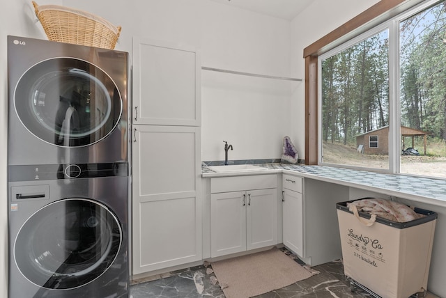 7617 S Cedar Rd, Spokane, WA 99224 - washroom featuring estacked washer and dryer, cabinet space, and dark marble finish flooring
