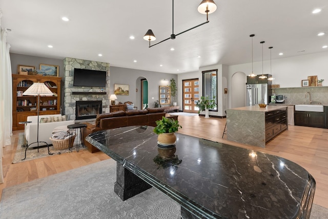 7617 S Cedar Rd, Spokane, WA 99224 - dining room featuring light wood-style flooring, a stone fireplace, arched walkways, and recessed lighting