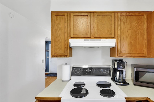 3511 W Francis Ave, Spokane, WA 99205 - kitchen with range, under cabinet range hood, stainless steel microwave, light countertops, and brown cabinets