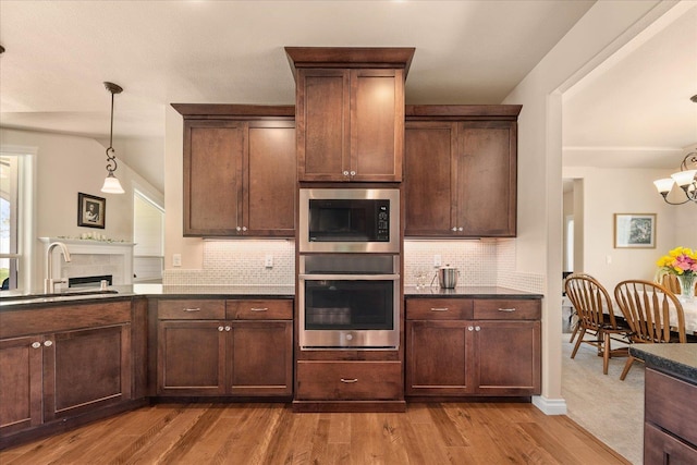9302 W Floyd Dr, Cheney, WA 99004 - kitchen with appliances with stainless steel finishes, dark wood-style flooring, decorative backsplash, dark countertops, and a chandelier